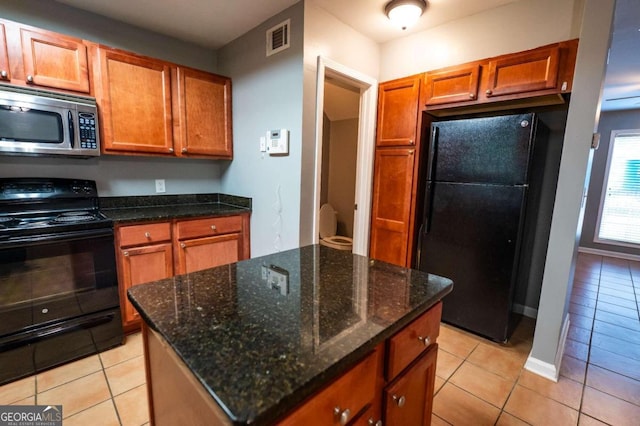 kitchen featuring dark stone counters, light tile patterned floors, and black appliances