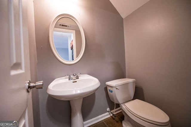 bathroom with vaulted ceiling, toilet, sink, and tile patterned floors