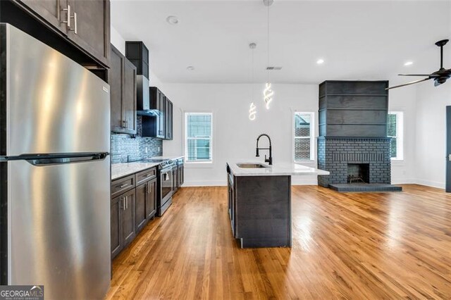 kitchen featuring a kitchen island with sink, sink, stainless steel appliances, and plenty of natural light