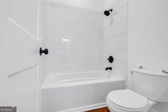 bathroom with tiled shower / bath combo and toilet