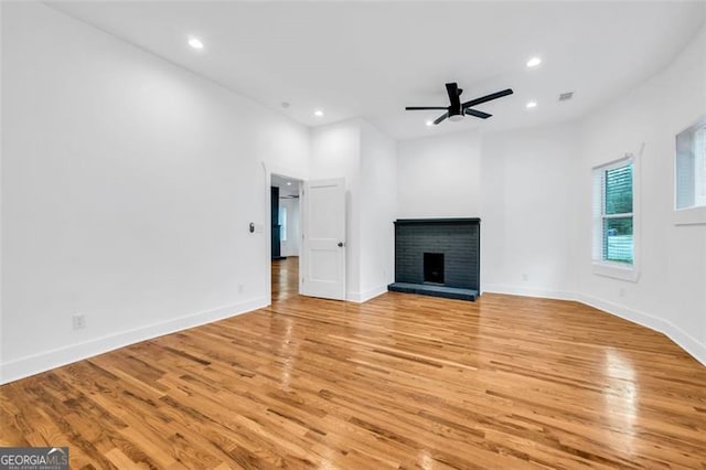 unfurnished living room with ceiling fan, light hardwood / wood-style flooring, and a brick fireplace