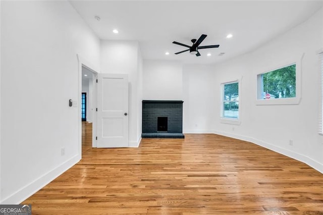 unfurnished living room featuring a fireplace, ceiling fan, and light hardwood / wood-style flooring