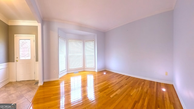 spare room with crown molding and light wood-type flooring