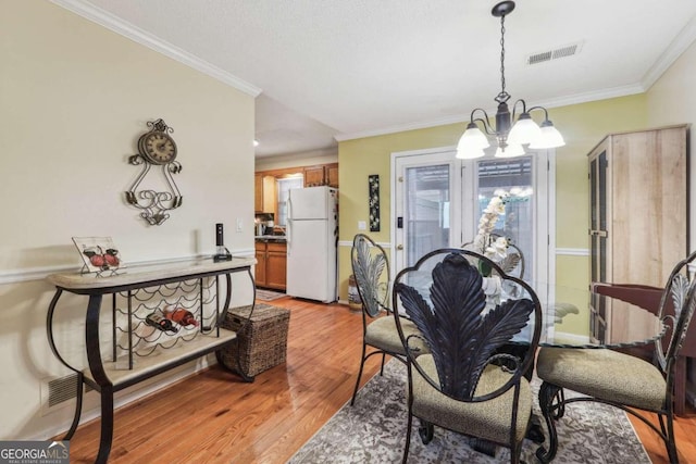 dining room featuring a notable chandelier, light wood-type flooring, and crown molding