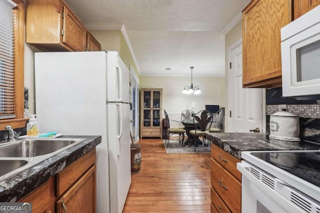 kitchen featuring hanging light fixtures, backsplash, white appliances, light hardwood / wood-style flooring, and a chandelier