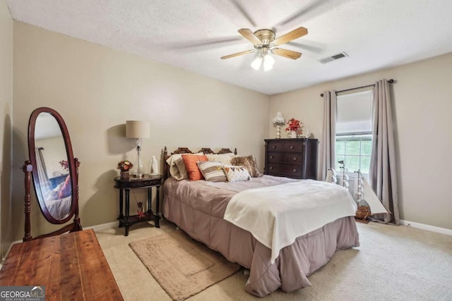 bedroom with light carpet, ceiling fan, and a textured ceiling