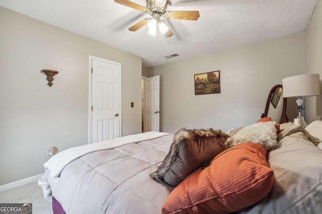 carpeted bedroom featuring ceiling fan and a textured ceiling