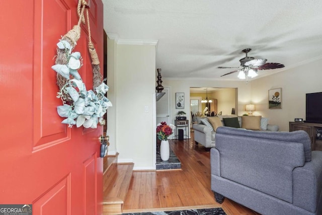 living room featuring wood-type flooring, ornamental molding, and ceiling fan