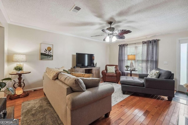 living room with ceiling fan, ornamental molding, a textured ceiling, and hardwood / wood-style floors