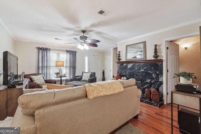 living room with ceiling fan, hardwood / wood-style flooring, crown molding, and a textured ceiling