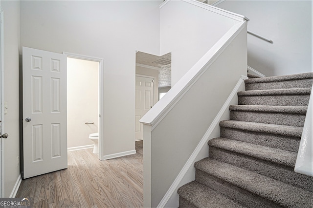 stairway featuring a high ceiling and hardwood / wood-style floors