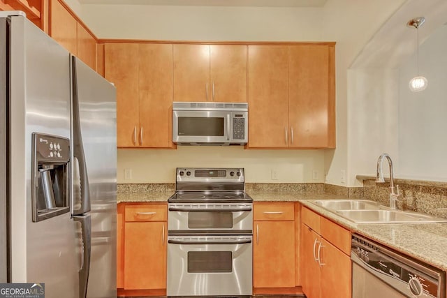 kitchen featuring light stone countertops, sink, appliances with stainless steel finishes, and hanging light fixtures