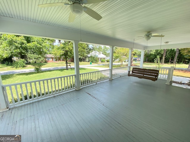 wooden terrace featuring a lawn, a porch, and ceiling fan