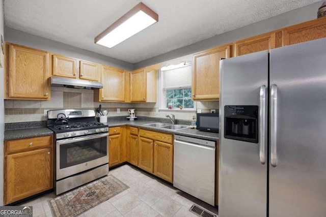 kitchen featuring stainless steel appliances, light tile patterned flooring, sink, a textured ceiling, and backsplash