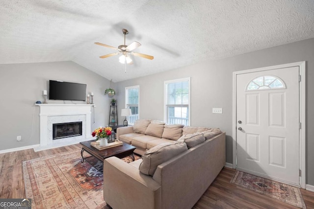 living room with dark wood-type flooring, a wealth of natural light, ceiling fan, and lofted ceiling