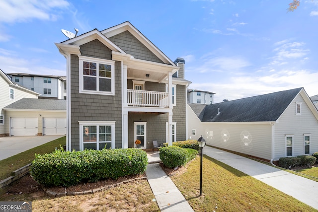 view of front of property featuring a balcony, a front lawn, and a garage