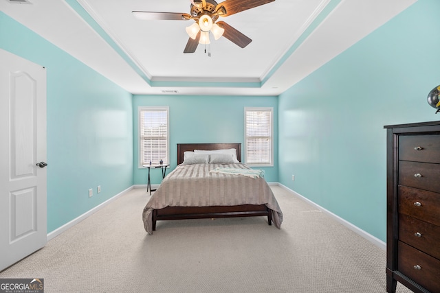 bedroom featuring ceiling fan, a raised ceiling, multiple windows, and light carpet