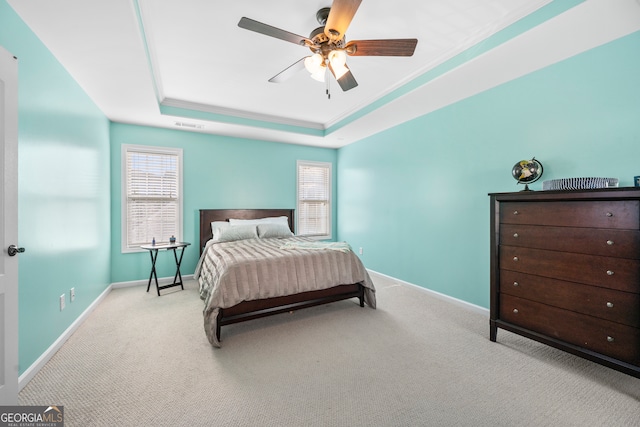 bedroom featuring light carpet, a tray ceiling, and ceiling fan