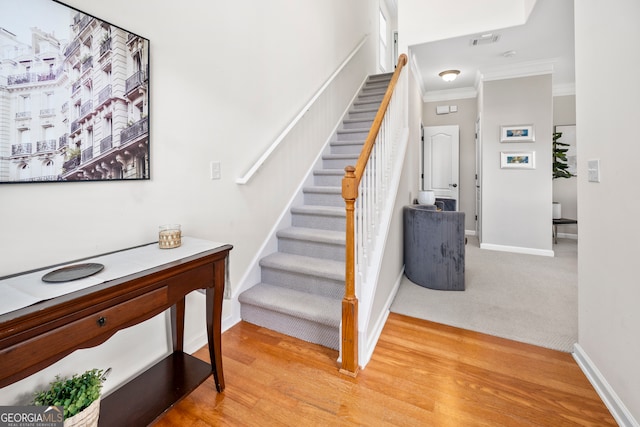 stairs with crown molding and hardwood / wood-style flooring