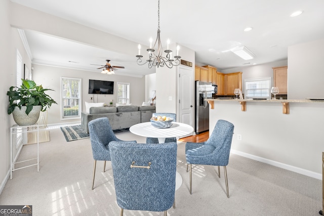 carpeted dining room featuring ornamental molding and ceiling fan with notable chandelier