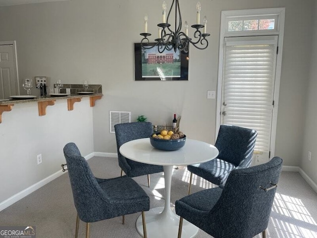 dining space featuring light carpet and a chandelier