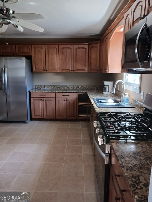 kitchen with ceiling fan, light tile patterned floors, sink, stainless steel appliances, and dark stone counters