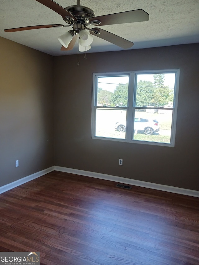 empty room featuring ceiling fan, dark hardwood / wood-style floors, and a wealth of natural light