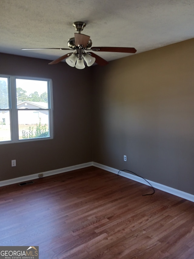 unfurnished room with ceiling fan, dark wood-type flooring, and a textured ceiling