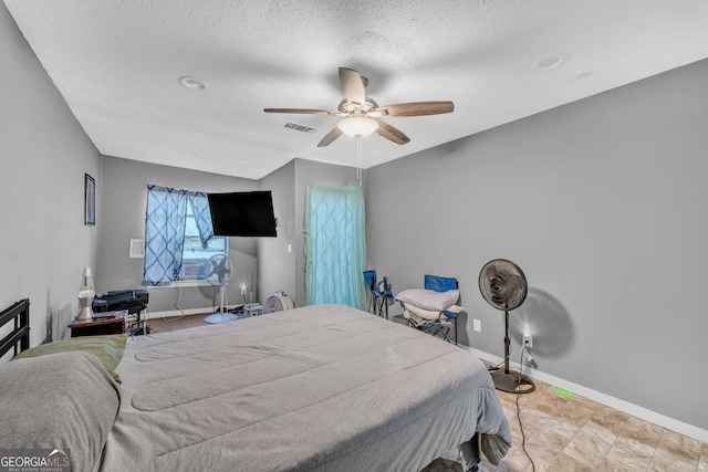 bedroom with ceiling fan and a textured ceiling