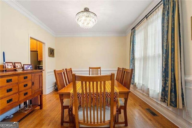 dining room with a healthy amount of sunlight, crown molding, and light hardwood / wood-style flooring