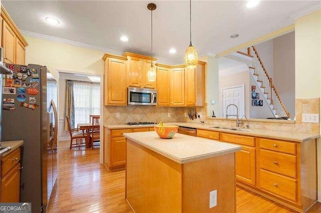 kitchen with appliances with stainless steel finishes, a kitchen island, crown molding, light hardwood / wood-style flooring, and sink