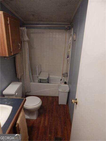 full bathroom featuring vanity, a textured ceiling, shower / bath combo with shower curtain, hardwood / wood-style flooring, and toilet