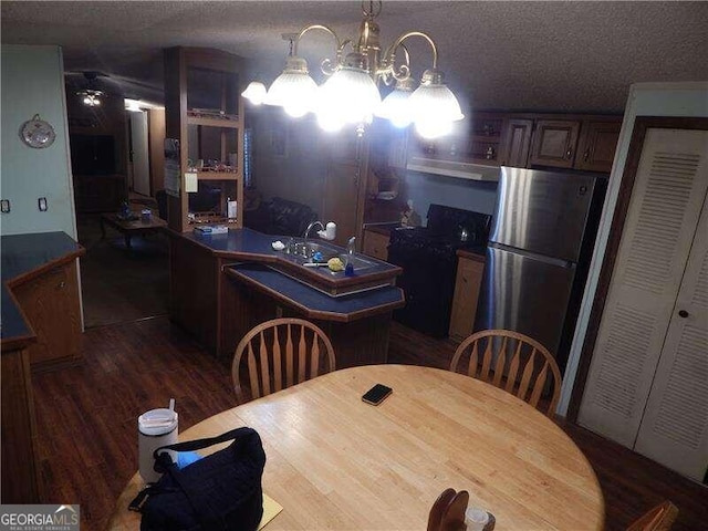 dining area featuring a textured ceiling, dark hardwood / wood-style floors, a notable chandelier, and sink