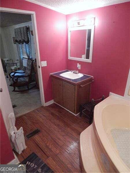 bathroom with vanity, hardwood / wood-style floors, and a textured ceiling