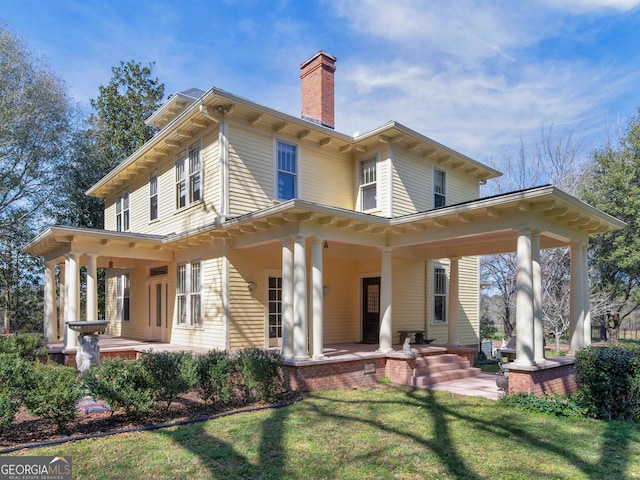 back of property with a lawn and covered porch