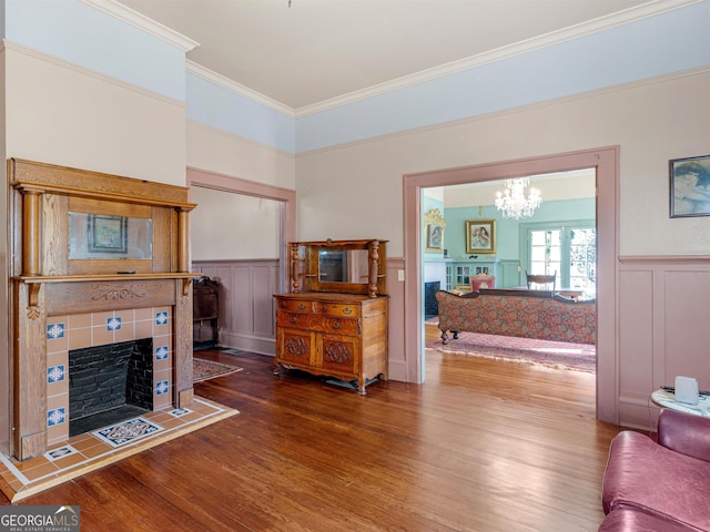 living room featuring an inviting chandelier, crown molding, a fireplace, and hardwood / wood-style floors