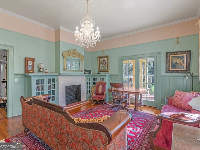 living room with an inviting chandelier, wood-type flooring, french doors, and crown molding