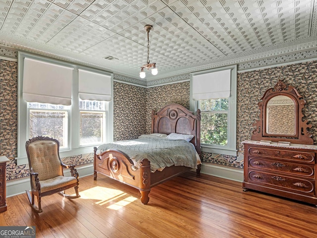 bedroom with multiple windows, wood-type flooring, and crown molding