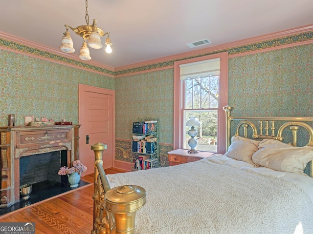 bedroom featuring an inviting chandelier, hardwood / wood-style flooring, and ornamental molding