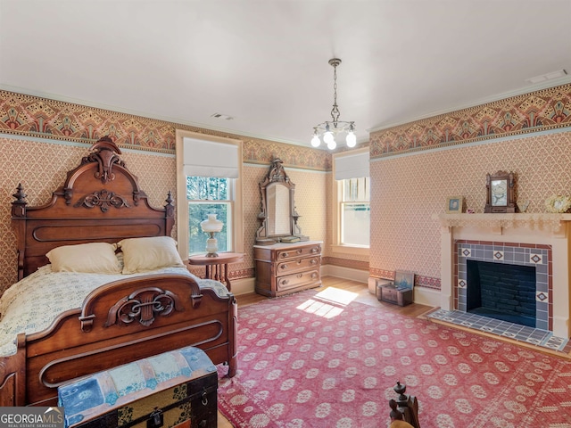 bedroom with hardwood / wood-style flooring, a tiled fireplace, and ornamental molding