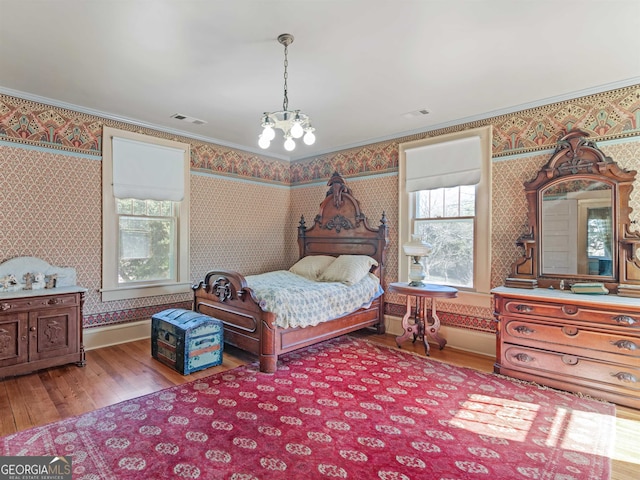 bedroom featuring ornamental molding, hardwood / wood-style floors, and a chandelier