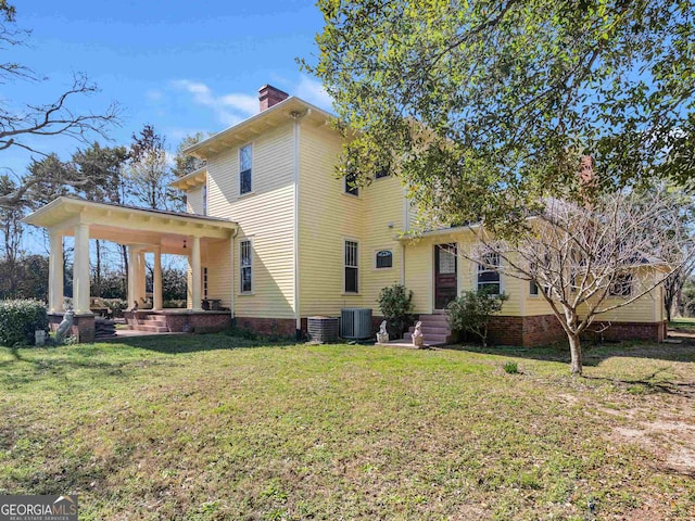 rear view of property featuring central AC unit and a yard