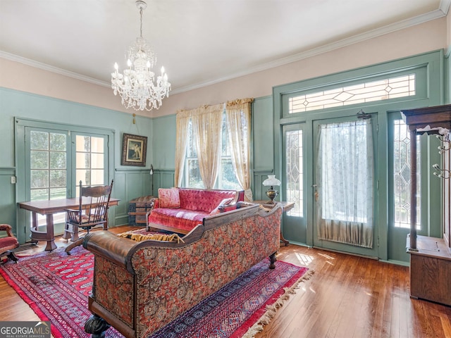 living room with a notable chandelier, crown molding, hardwood / wood-style floors, and a healthy amount of sunlight