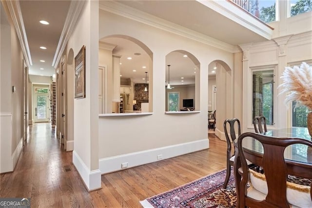 dining area featuring wood-type flooring, plenty of natural light, and crown molding