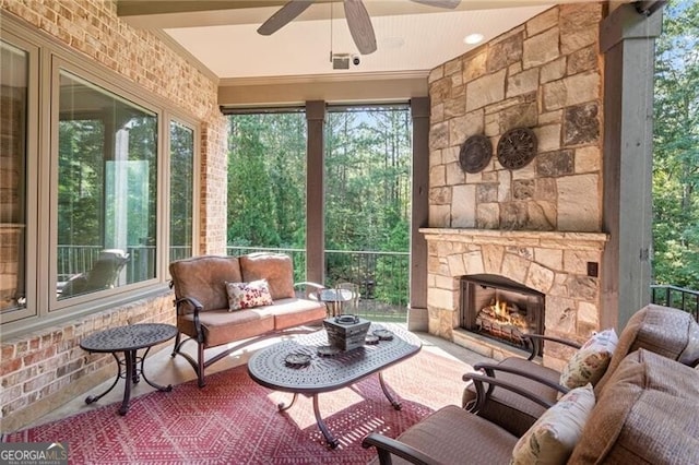 sunroom featuring ceiling fan, an outdoor stone fireplace, and plenty of natural light