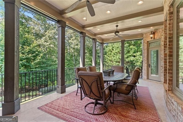 sunroom with ceiling fan, plenty of natural light, and beam ceiling