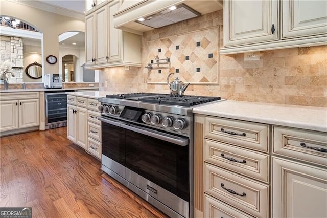 kitchen with custom exhaust hood, wine cooler, tasteful backsplash, high end range, and dark wood-type flooring