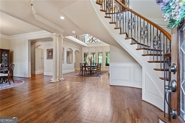 entryway featuring ornamental molding, decorative columns, and dark wood-type flooring