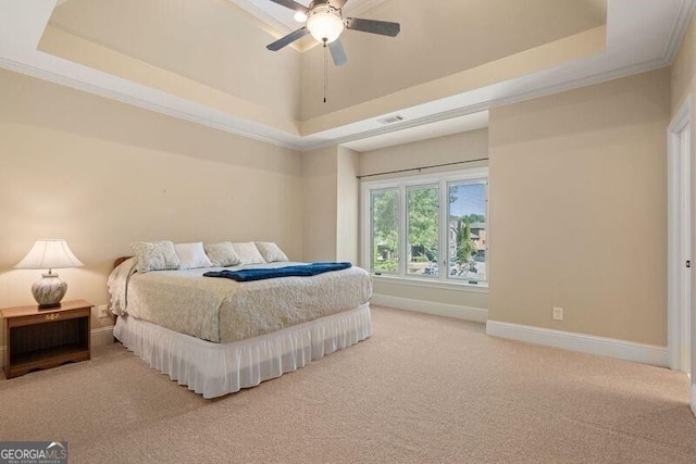 carpeted bedroom with ceiling fan, a tray ceiling, and ornamental molding