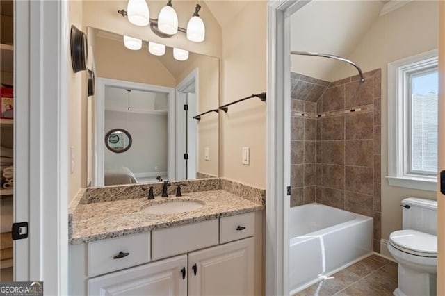 full bathroom featuring vaulted ceiling, tiled shower / bath combo, tile patterned floors, vanity, and toilet